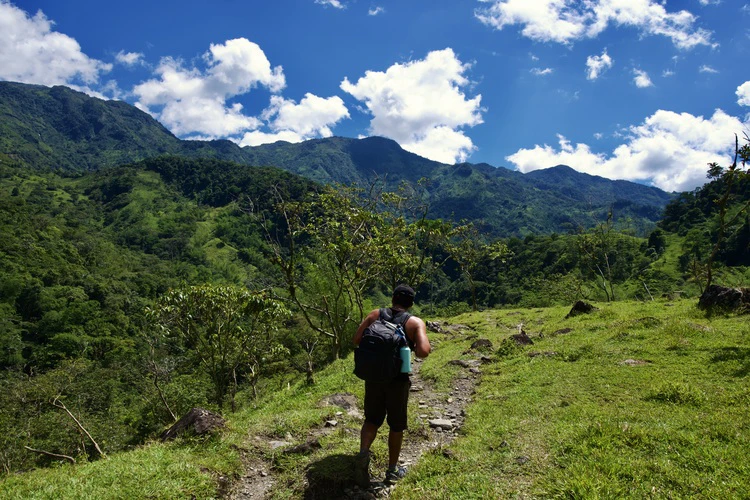 hiker in the sunny valle de las cascadas surrounded by mountains in the distance